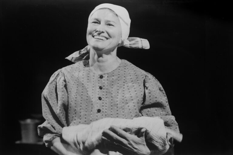 Eeva-Maija Haukinen rooliasussa, lakanakäärö käsissään.