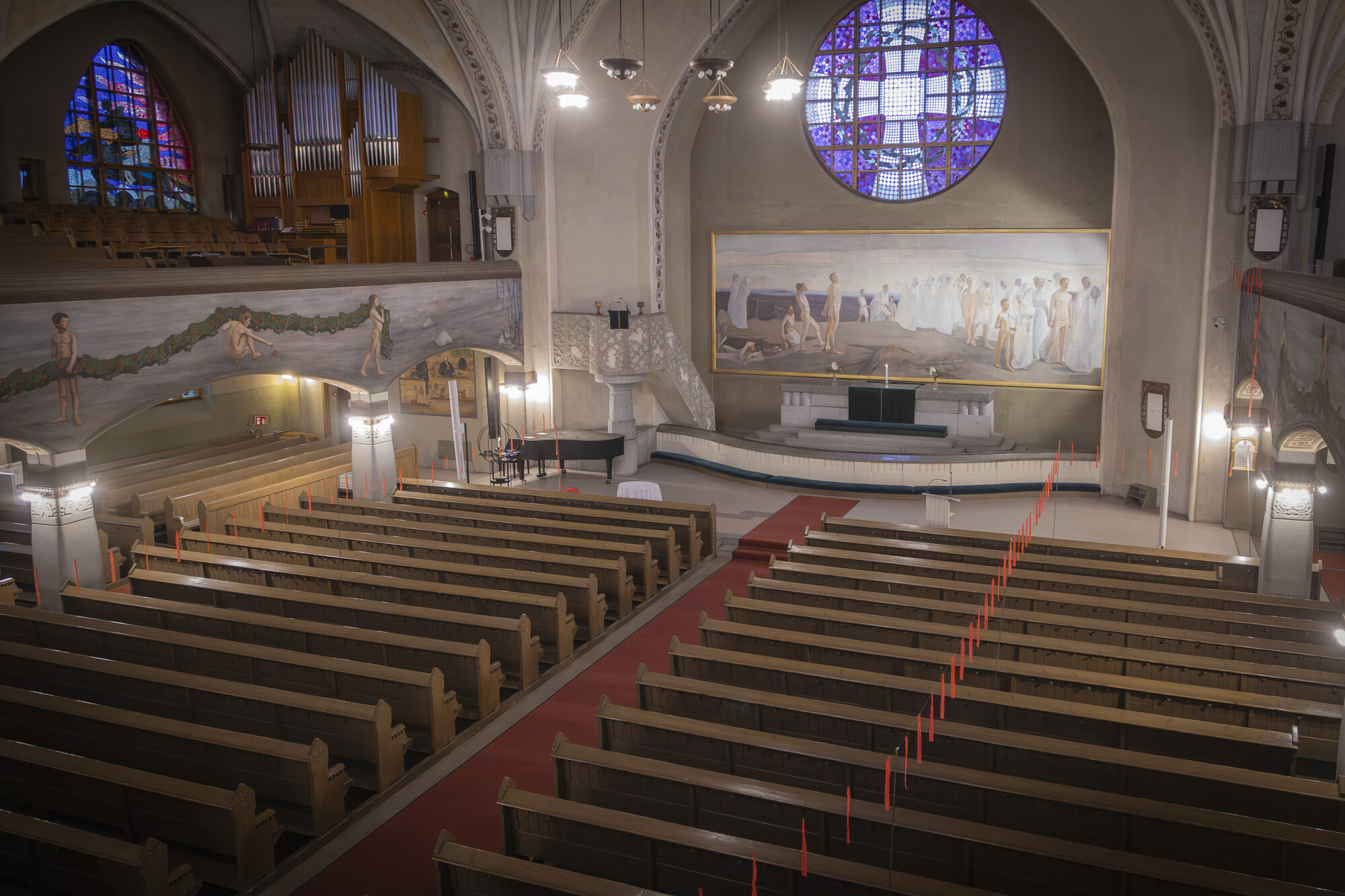 Näkymä kirkkotilasta. Tilaan on ripustettu punaisia nauhoja.