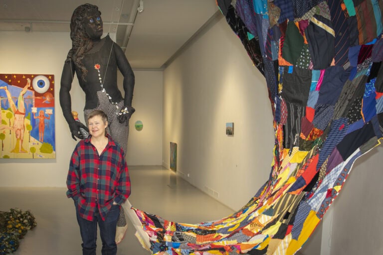 Pauliina Turakka Purhonen galleriatilassa, taideteoksia taustalla.