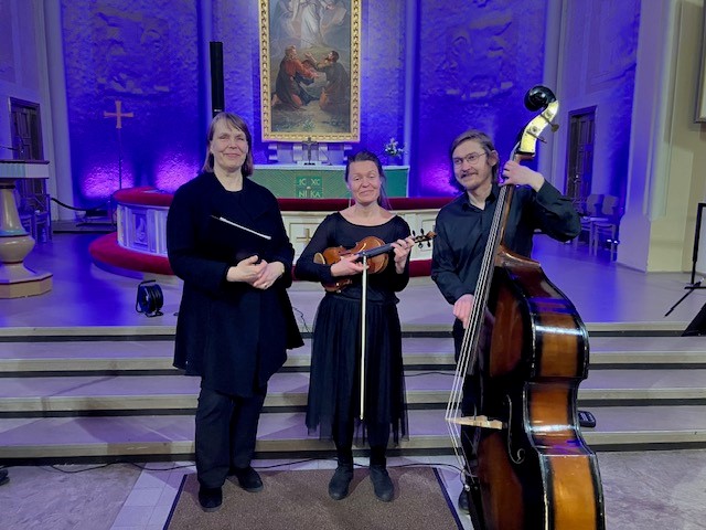 Kolme muusikkoa alttarin edustalla.