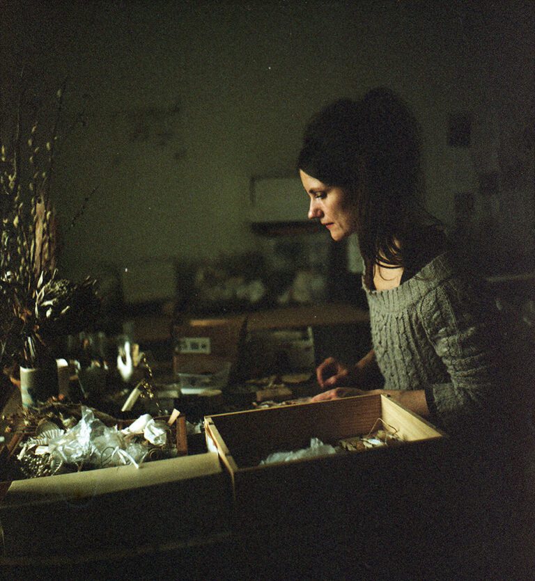 Taiteilija Kristiina Karsten tekee taideteosta pöydän äärellä.