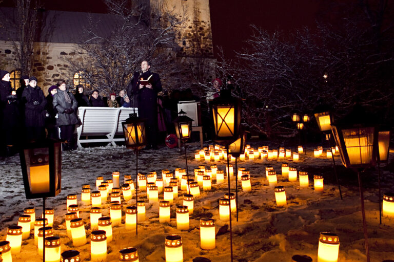 Hautakynttilöitä ja taustalla ihmisiä.