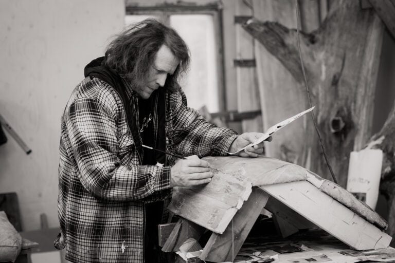 Taiteilija Paavo Paunu maalaa sivellin ja paletti käsissään. Kuva: Heli Nukki