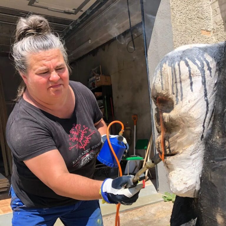 Taiteilija Reetta Gröhn-Soininen työstää taideteosta tohottimella.